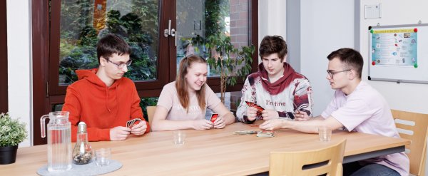 Gruppe aus vier Auszubildenen spielt das Kartenspiel Uno.